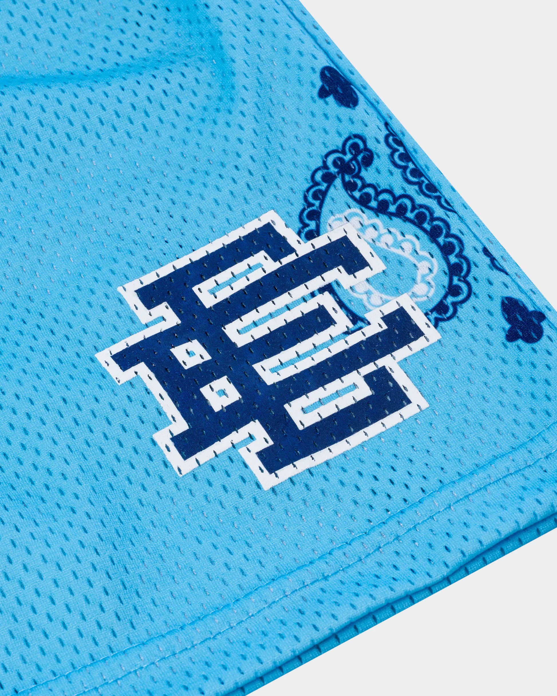 Close-up of blue designer athletic shorts for summer with printed navy logo and paisley pattern