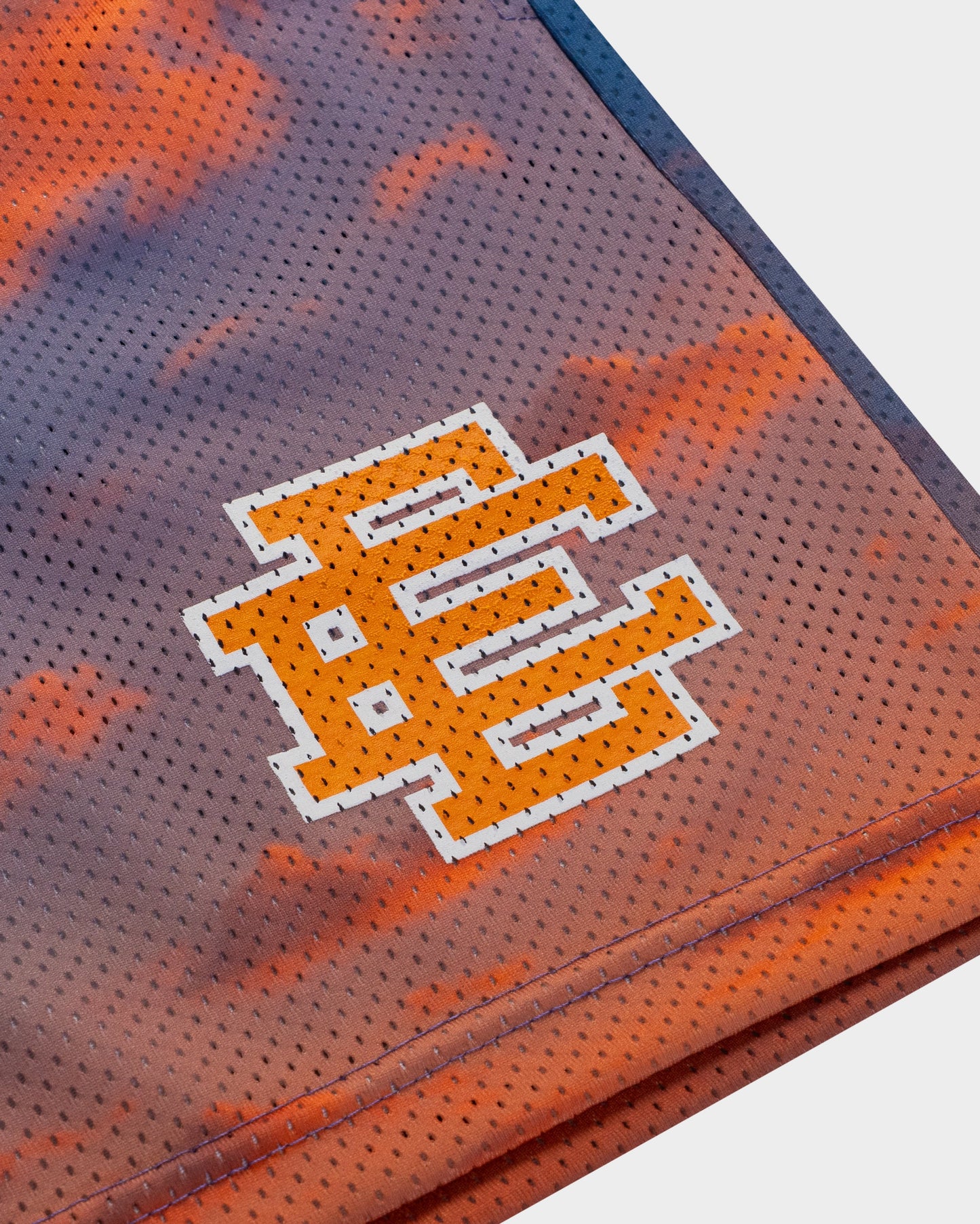 Close-up of premium designer athletic shorts with orange and purple mesh fabric and stitched logo